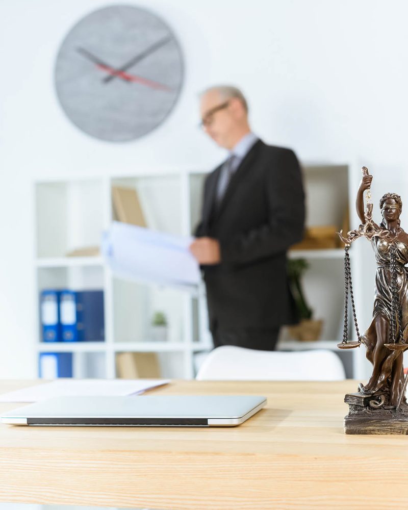 femida sculpture on table with blurred mature lawyer on background